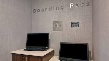 A desk with two laptops, a sign reading "Boarding Pass," and a directional sign.