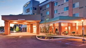 Un hôtel Courtyard Marriott doté d’un espace extérieur couvert avec des sièges, d’une entrée bien visible et d’un parking.