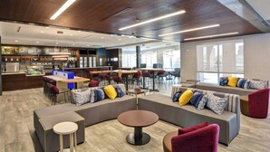 Un espace de détente moderne, doté de différents types de sièges, d’un bar et d’une grande fenêtre laissant entrer la lumière naturelle.