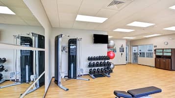 A gym with exercise equipment, a bench, and a wall-mounted TV.