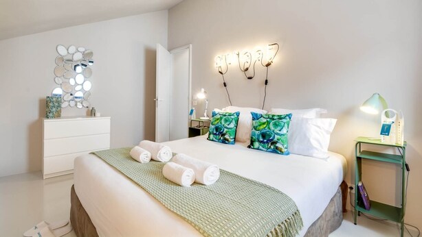 A neatly arranged bedroom with a bed, pillows, a bedside table, a lamp, and a wall-mounted mirror. - Sweett | Brune IX - Two Bedroom Apartment, Sleeps 6 (Paris)