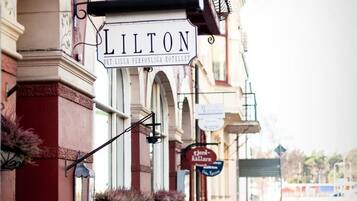 Un hotel llamado 'LILTON' de estilo arquitectónico clásico, que presenta un balcón con plantas en macetas y un cartel.