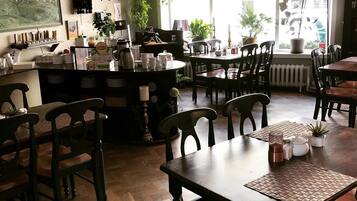 Una cafetería acogedora con mobiliario de madera, una estación de café y ventanas amplias con plantas.