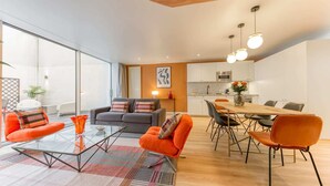 A modern living space with a glass partition, a sofa, a dining table with chairs, and a kitchen area. - Sweett | Brune I - Two Bedroom Apartment, Sleeps 6 (Paris)