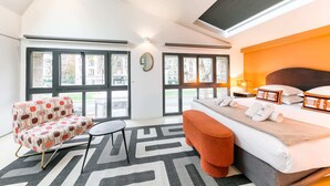 A modern hotel room with a large bed, a sofa, and a view of the city through large windows. - Sweett | Brune I - Two Bedroom Apartment, Sleeps 6 (Paris)