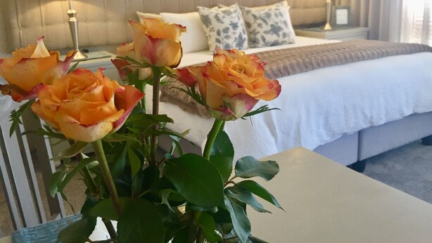 Een hotelkamer met een bed, twee bedlampen en een vaas met rozen.