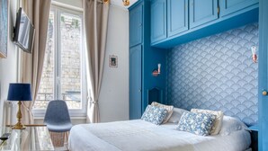 A bedroom with a bed, a chair, a table, and a TV. - Hôtel Le Bretagne (Vannes)