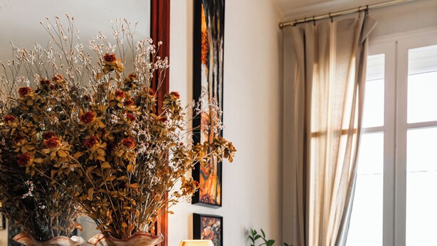 A room with a dining table, chairs, a vase with dried flowers, a lamp, and a radiator. - Hôtel Le Bretagne (Vannes)
