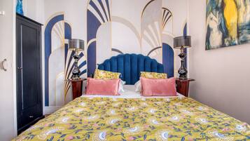 A bedroom with a bed, two bedside tables, a wardrobe, and a large abstract painting on the wall.