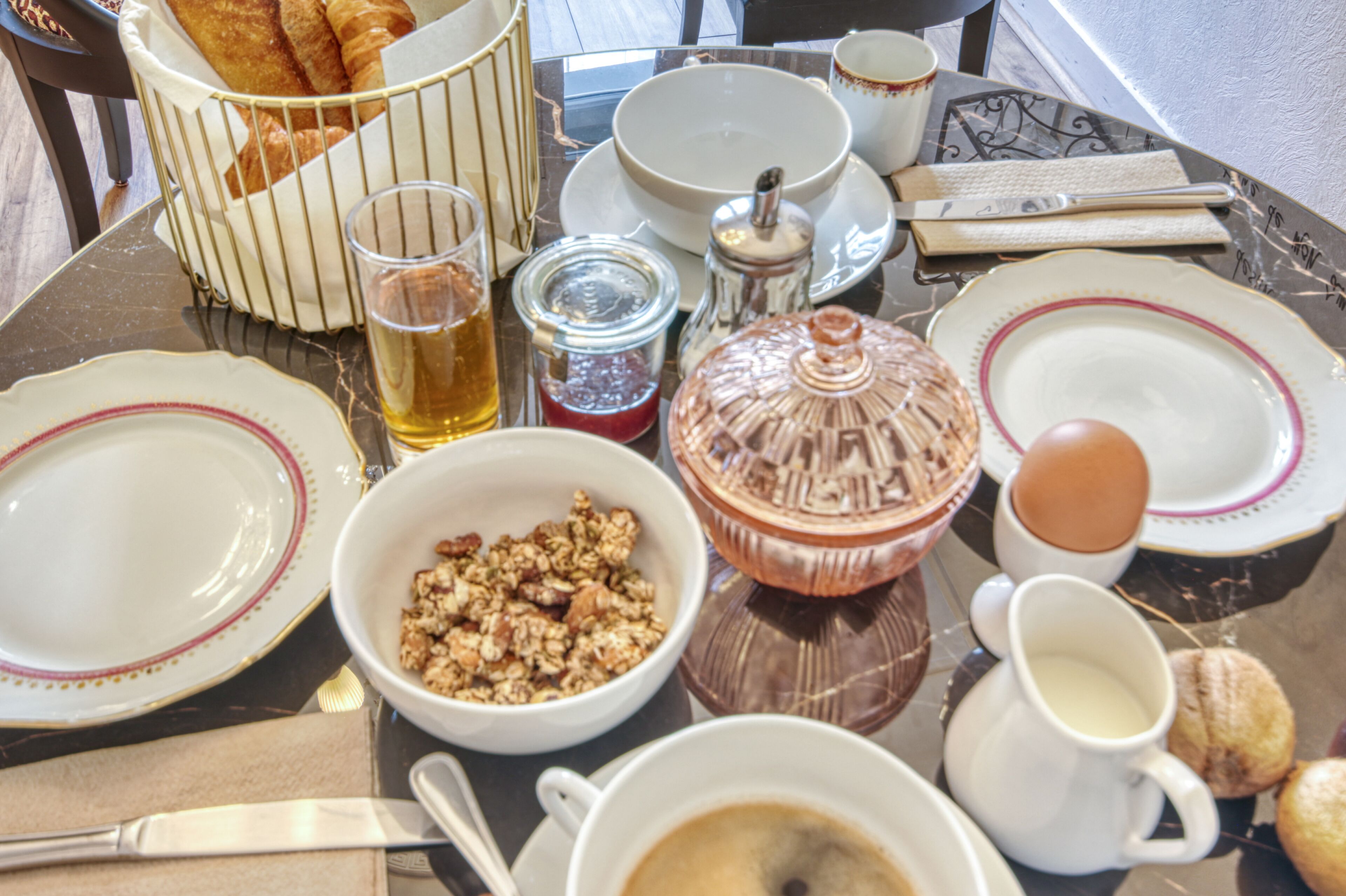 A dining table with various breakfast items including bread, cereal, eggs, and beverages.