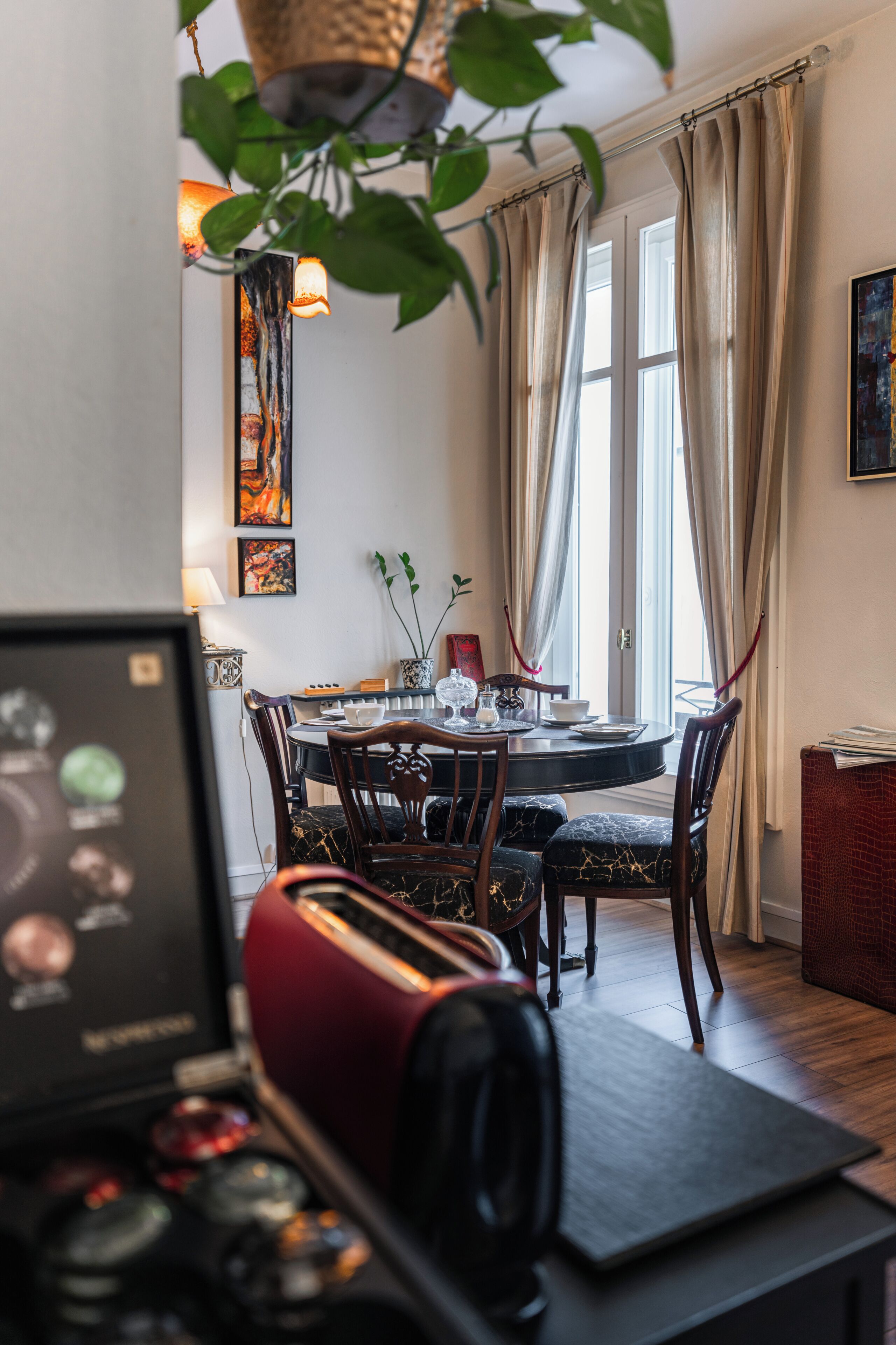 Un comedor con una mesa redonda, sillas y un ordenador portátil sobre un escritorio.