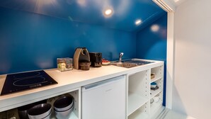 Una cocina moderna con una pared azul de acento, horno empotrado, cafetera y pileta.