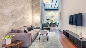 A modern living room with a sofa, a coffee table, and a TV mounted on the wall. - Sweett | Artois - Three Bedroom Apartment, Sleeps 6 (Paris)