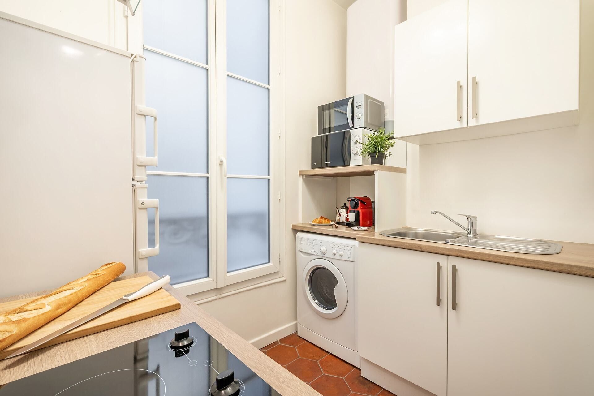 A compact kitchen with a washing machine, microwave, and a small sink.