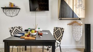 A dining area with a black table, patterned chairs, a TV, and a wooden cabinet with a Mickey Mouse sketch.