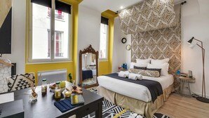 A modern bedroom with a bed, bedside table, mirror, and a window with a view.