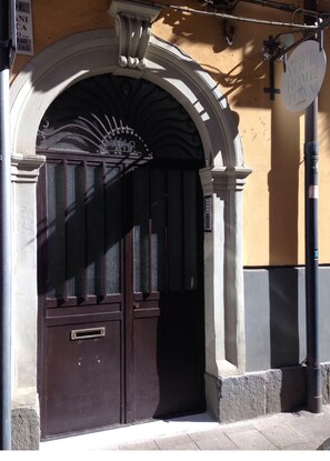 Traditional entrance with a dark brown door and arched window above, set against a light yellow facade.