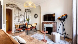 Ein Wohnzimmer mit Sofa, Couchtisch, Kamin, Fernseher und Stehlampe.