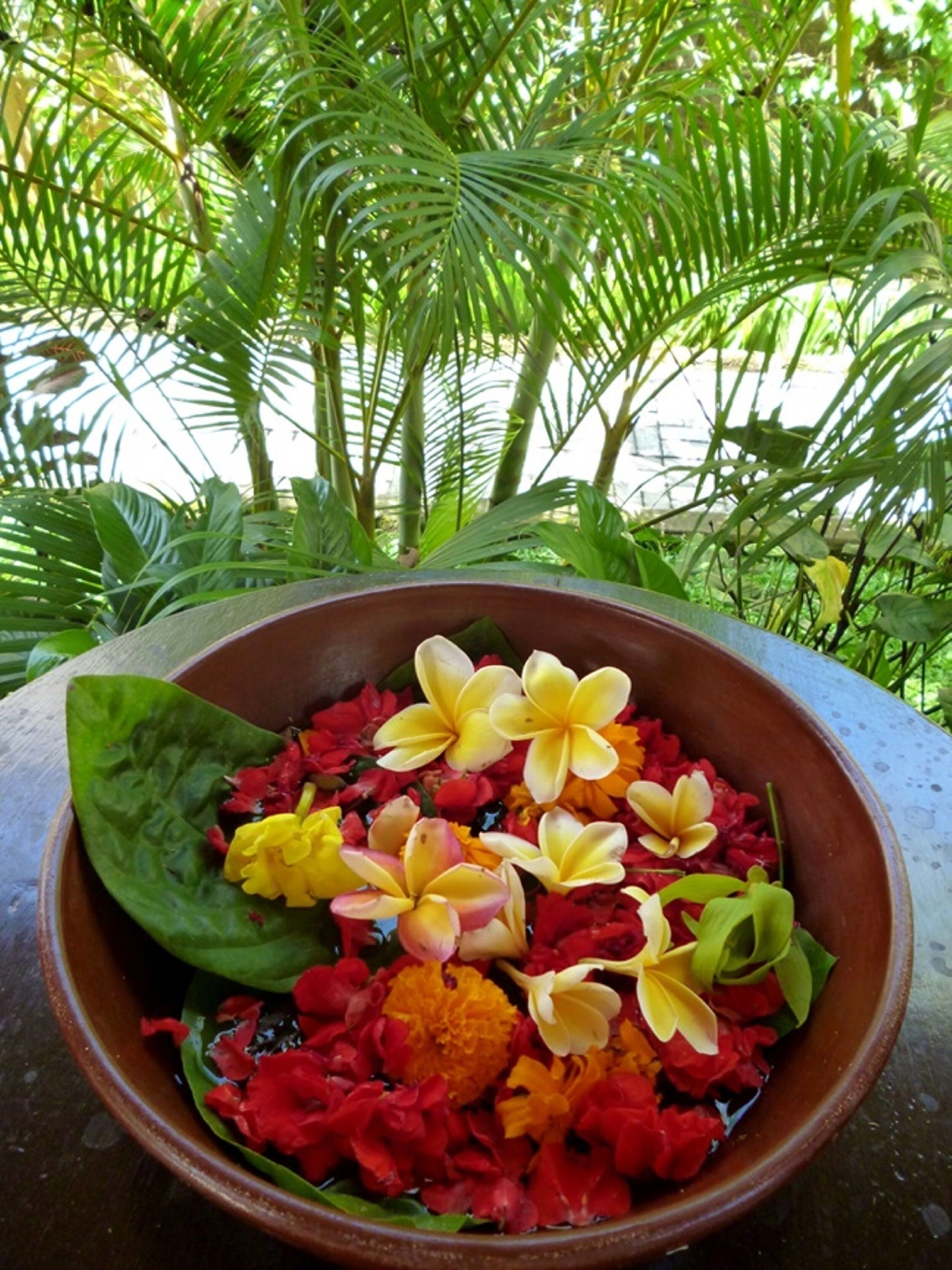 Un vaso di fiori su un tavolo con sfondo tropicale.