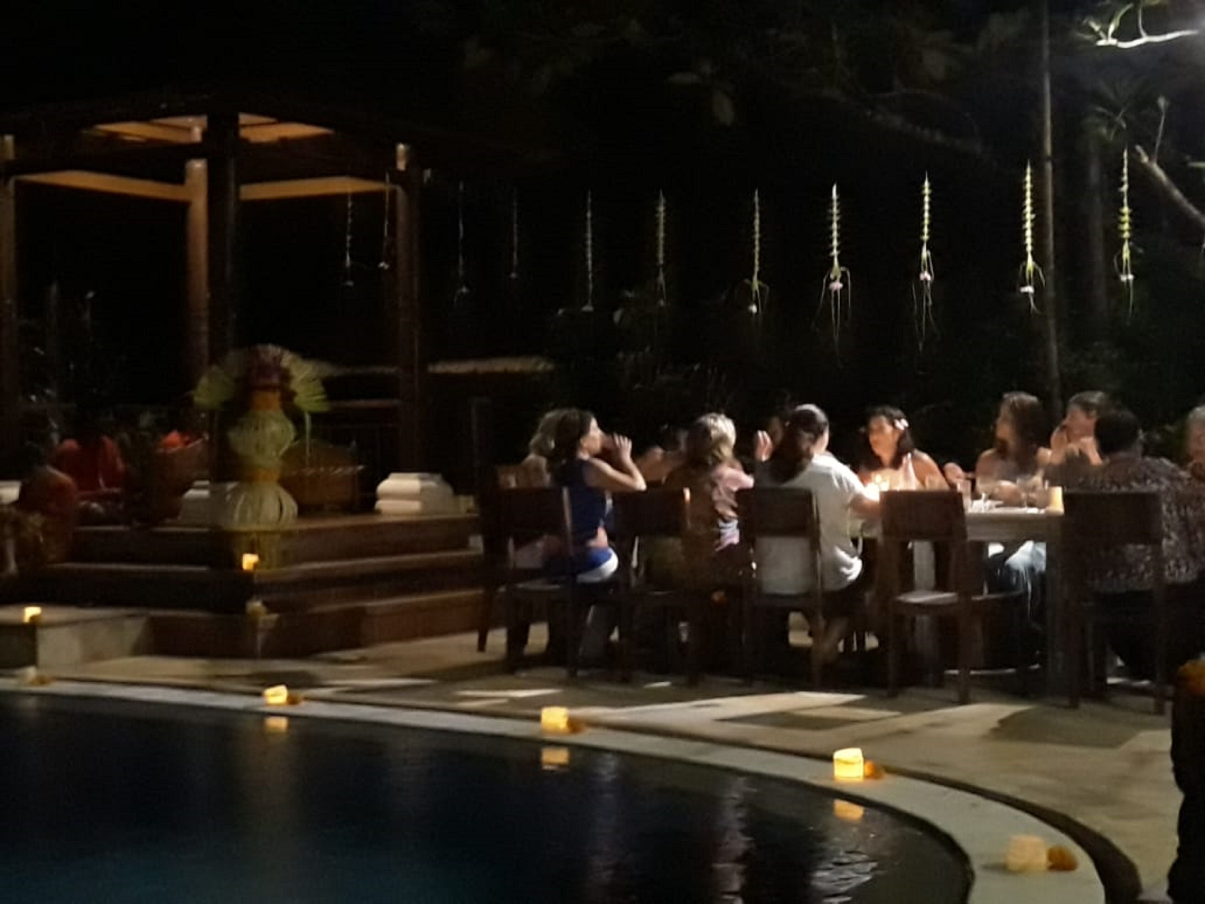 Ein Essbereich im Freien mit Tischen und Stühlen, ein Pool und eine Laube.