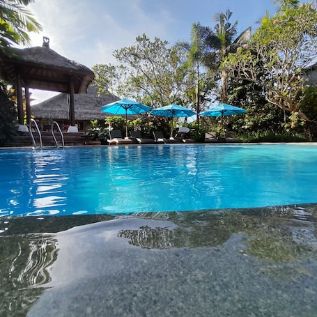 Una piscina al aire libre, sombrillas, sillones reclinables de piscina