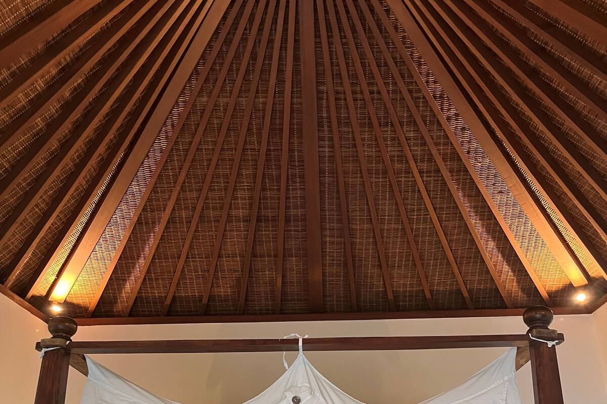 A room with a wooden ceiling and a canopy bed.