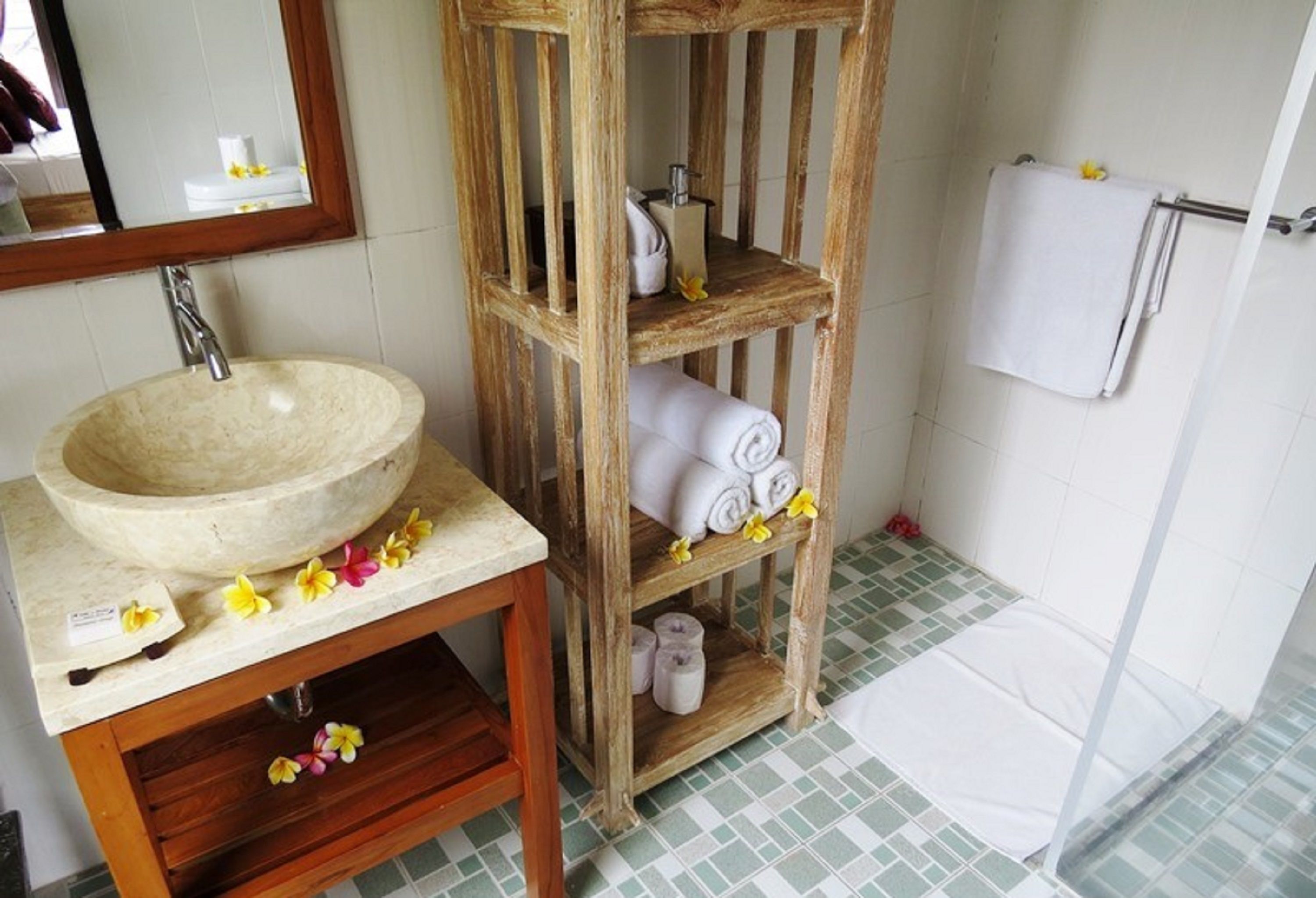 A bathroom with a wooden vanity, a large sink, and a shower area.