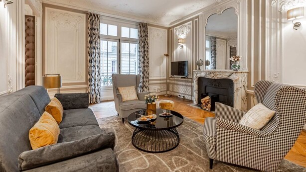 A classic living room with a fireplace, two armchairs, a sofa, and a coffee table.