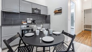 A modern kitchen with grey cabinets, a black countertop, and a dining table set for four.
