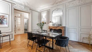 A dining room with a large table set for six, flanked by chairs, a fireplace, and a mirror.