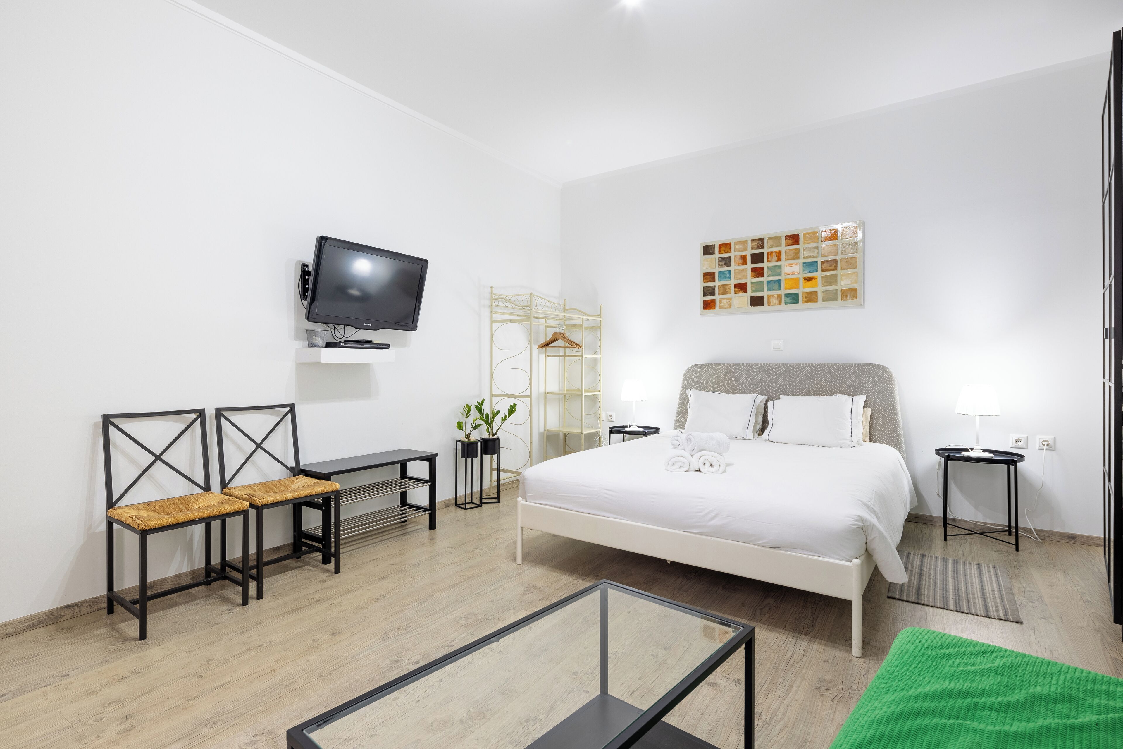 A modern hotel room with a bed, a TV, a desk, and a chair.
