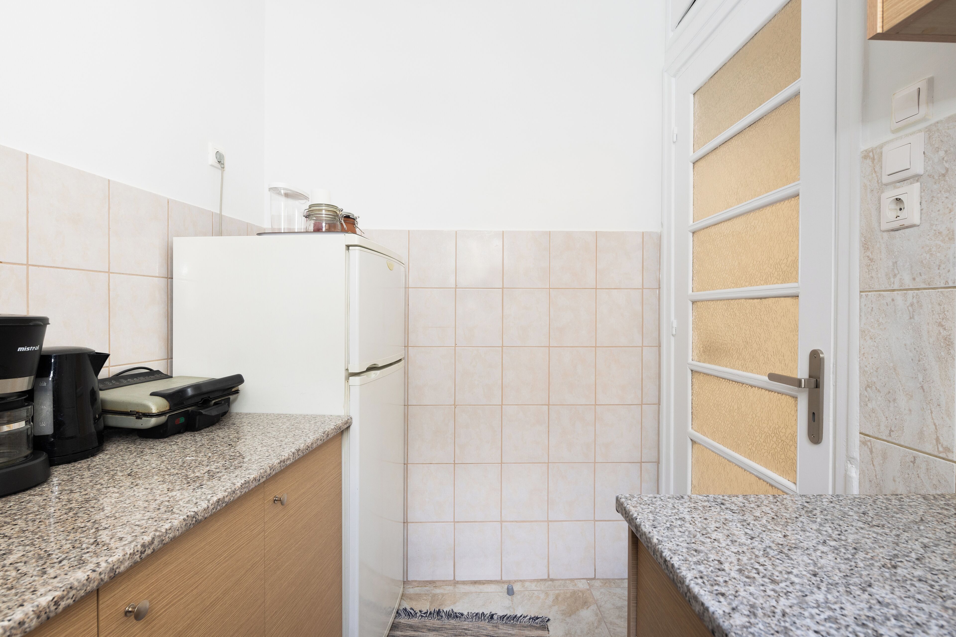 Een keuken met een witte koelkast, een koffiezetapparaat en een broodrooster op het aanrecht.