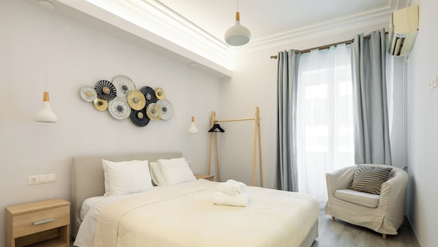 Un dormitorio moderno con una cama grande, mesitas de noche, una silla y una obra de arte en la pared.