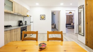 Cocina compacta con armarios de madera, una mesa de comedor con dos sillas y un cuenco de fruta.