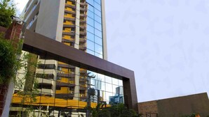 A modern high-rise building with a glass facade, a rooftop terrace, and a landscaped courtyard with plants. - Fity Hotel (Recife)