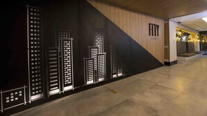 A hotel interior with a modern design, featuring a wall with a cityscape mural, a wooden ceiling, and a seating area with a view of the city. - Fity Hotel (Recife)