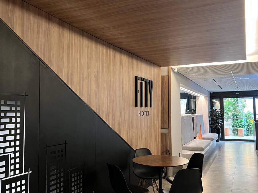 Un moderno vestíbulo de hotel con una pared de madera, un letrero que dice 'HOTEL', una zona de estar y una escalera.