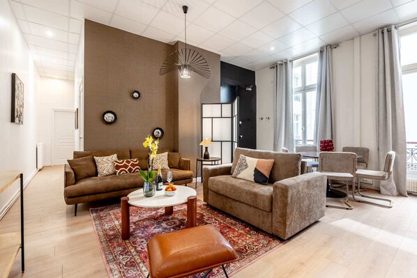 A modern living room with a brown sofa, a coffee table, and a patterned rug.