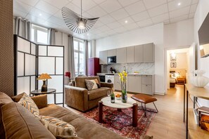 A modern living room with a sofa, coffee table, and a dining area with a table and chairs.