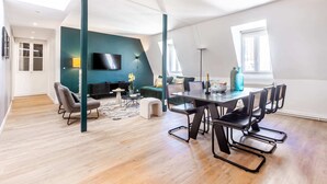 Ein moderner Wohnraum mit Essbereich, Fernseher und Blick auf die Stadt.