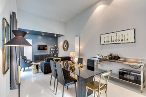 Uma sala de estar moderna com sofá, cadeiras, uma mesa de jantar e uma cozinha com pia e forno.