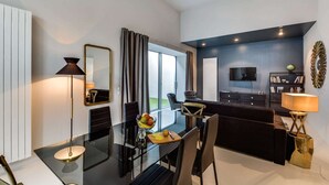 A modern living room with a glass dining table, a sofa, and a TV mounted on the wall. - Sweett | Brune III - Three Bedroom Apartment, Sleeps 8 (Paris)