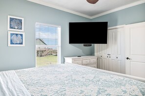 A bedroom with a bed, a TV mounted on the wall, a window with blinds, and a door with a cabinet. - Miller's Landing (Port Bolivar)