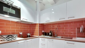 A modern kitchen with white cabinets, a red-tiled backsplash, and stainless steel appliances. - Sweett | Milan IV - Three Bedroom Apartment, Sleeps 8 (Paris)
