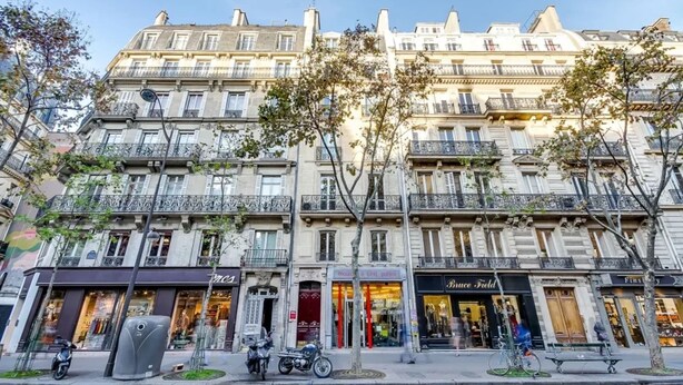 A multi-story building with storefronts on the ground floor, including a clothing store and a shoe store. - Sweett | Saint Germain IV (Paris)