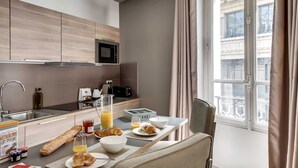 Una cuina moderna amb zona de menjador, esmorzars preparats i vista a la ciutat.