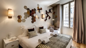 Habitació d'hotel amb un llit gran, taules de nit, una obra decorativa a la paret i una finestra amb cortines.