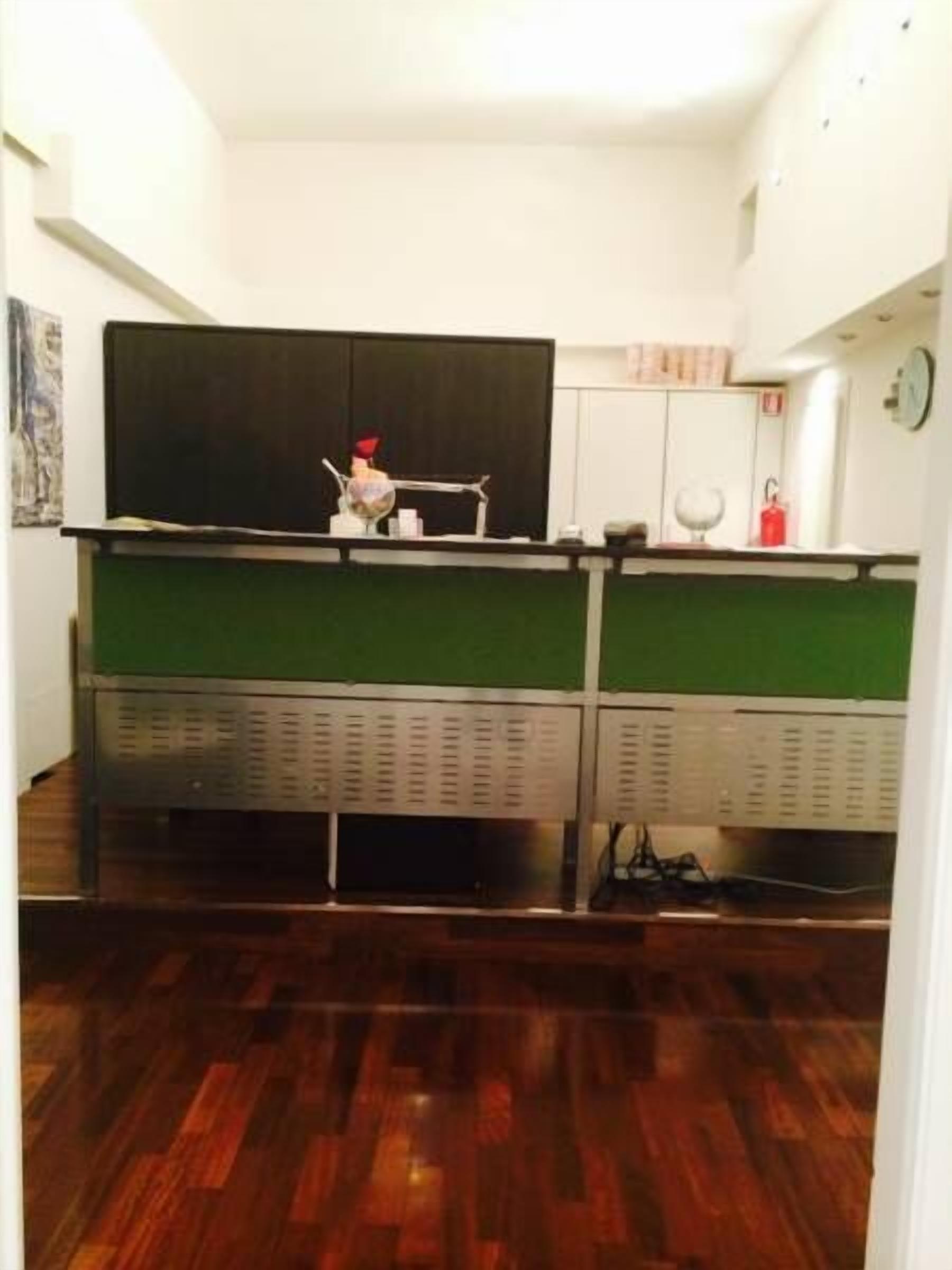 A compact kitchen with a green countertop, white cabinets, and a black backsplash.