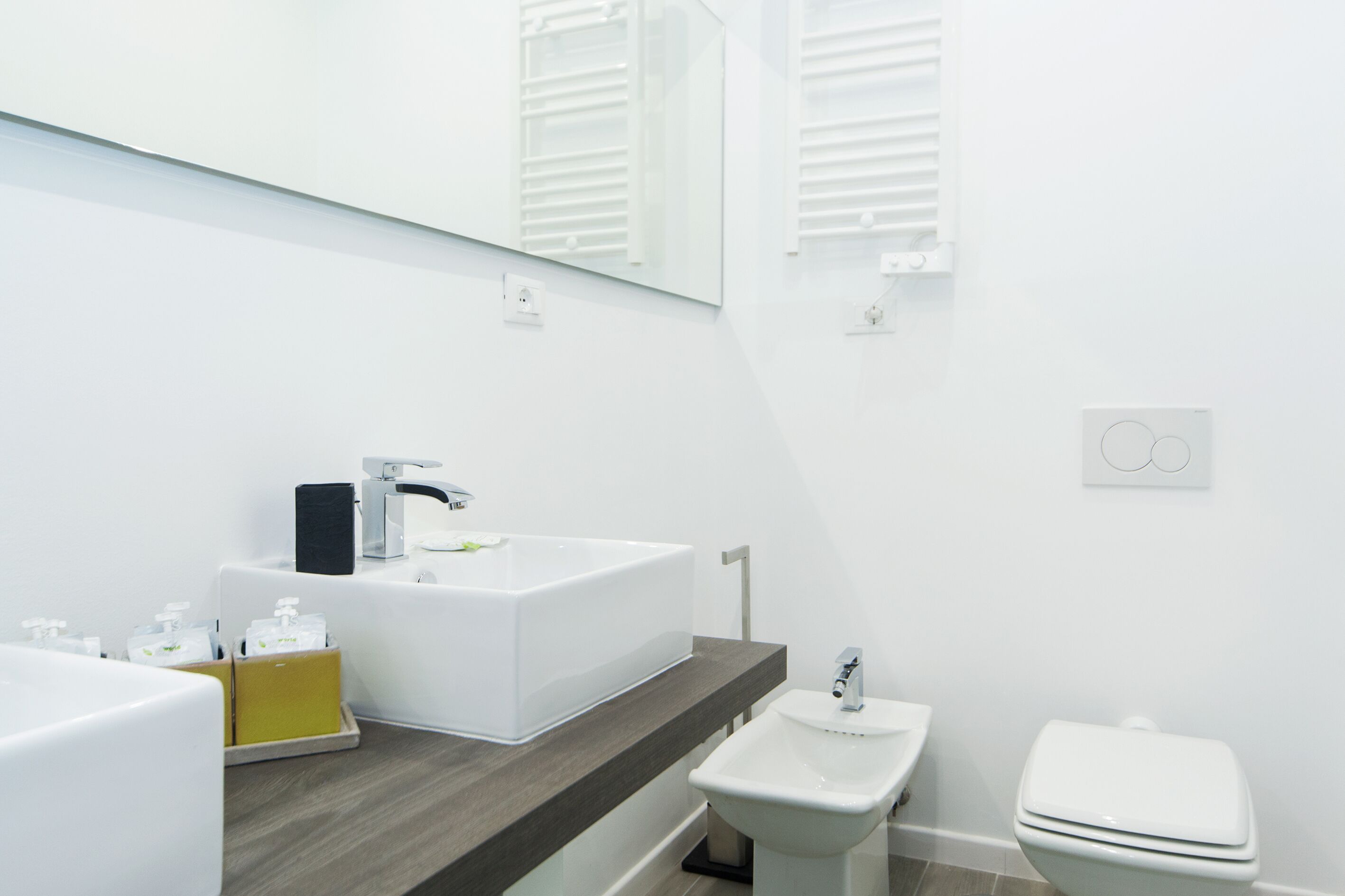 A modern bathroom with a large white sink, a bidet, and a toilet.