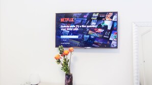 A flat-screen TV mounted on a wall displaying a Netflix interface with various TV and film options. - Casa Bella Pantheon (Rome)